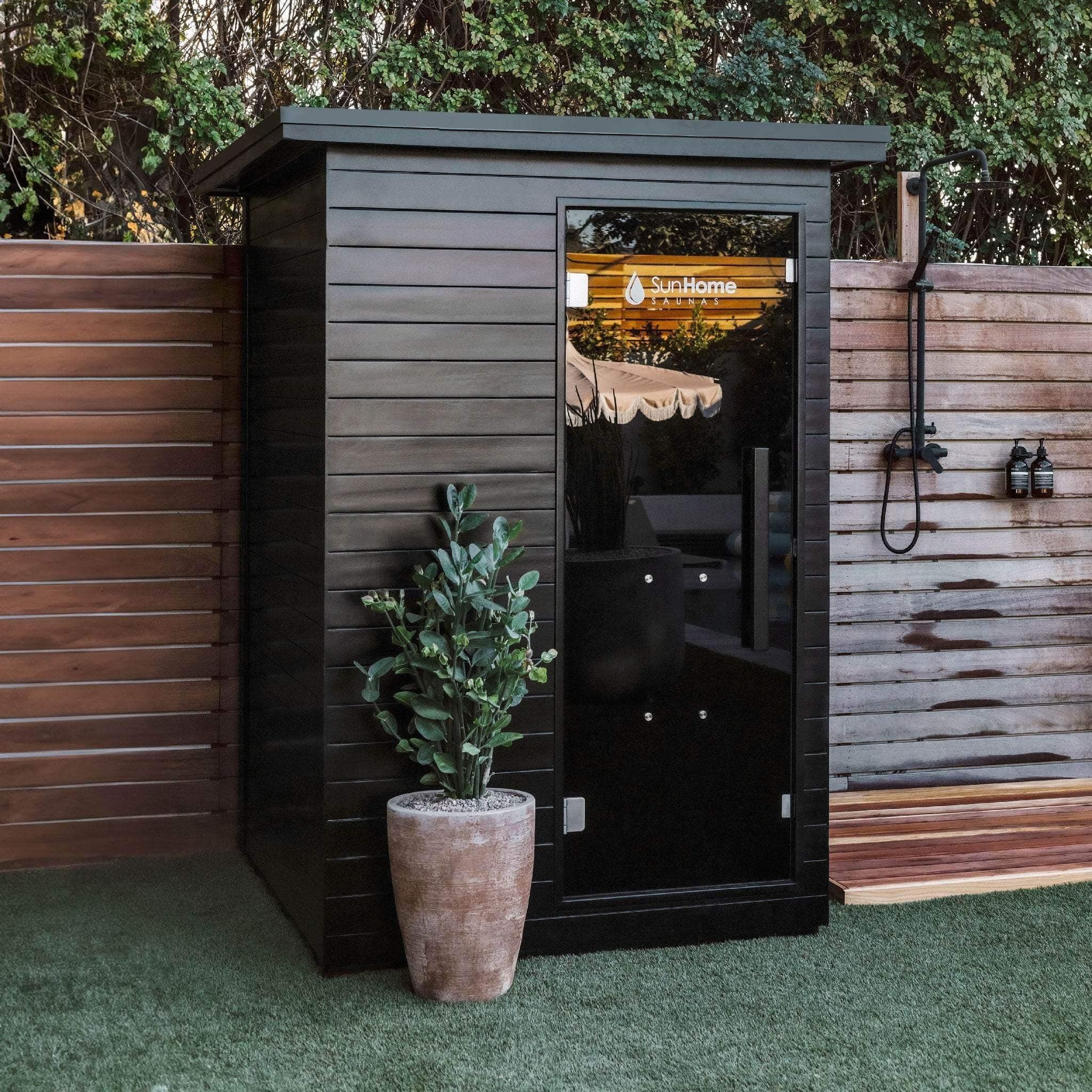 Sun Home Luminar 2-Person beside a wood fence and potted plant